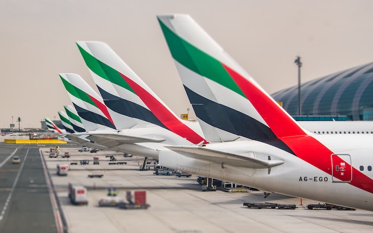 Multiple tails of Emirates airplanes parked at the gates – Image by Guy Roberts on Unsplash (https://unsplash.com/photos/uwbjm6-Ti-k)